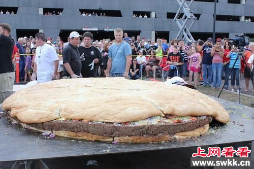 人们正在围观一个直径约3米，重量超过1吨的培根芝士汉堡