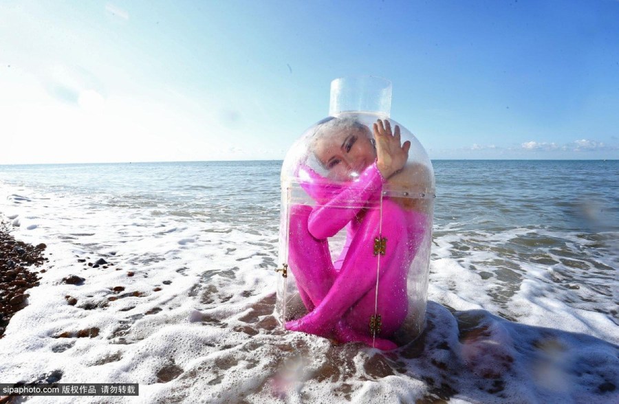 英国Zippo马戏团柔术女孩Odka在海滩展示柔术，将自己装进一个“漂流瓶”