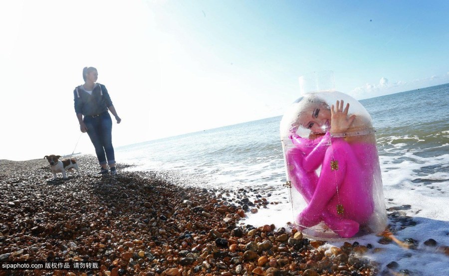 英国Zippo马戏团柔术女孩Odka在海滩展示柔术，将自己装进一个“漂流瓶”