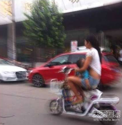女子边骑摩托车边撩起衣服给孩子喂奶
